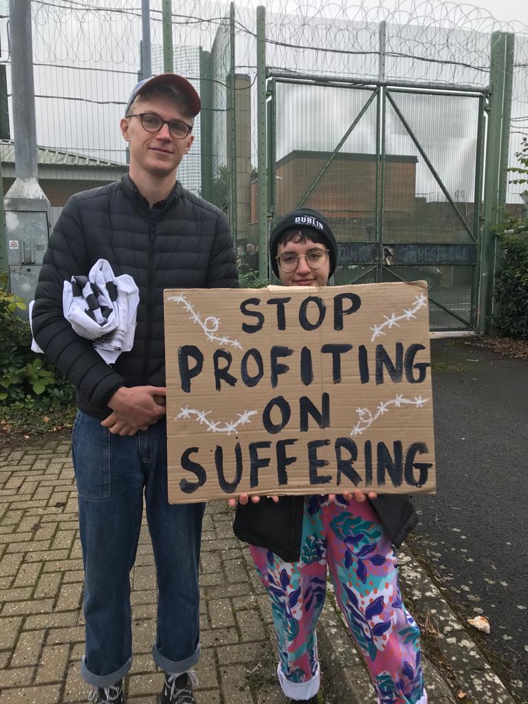 Protesters with placards in front of barbed wire (Photo by Liz Peretz / Geoff Taylor)