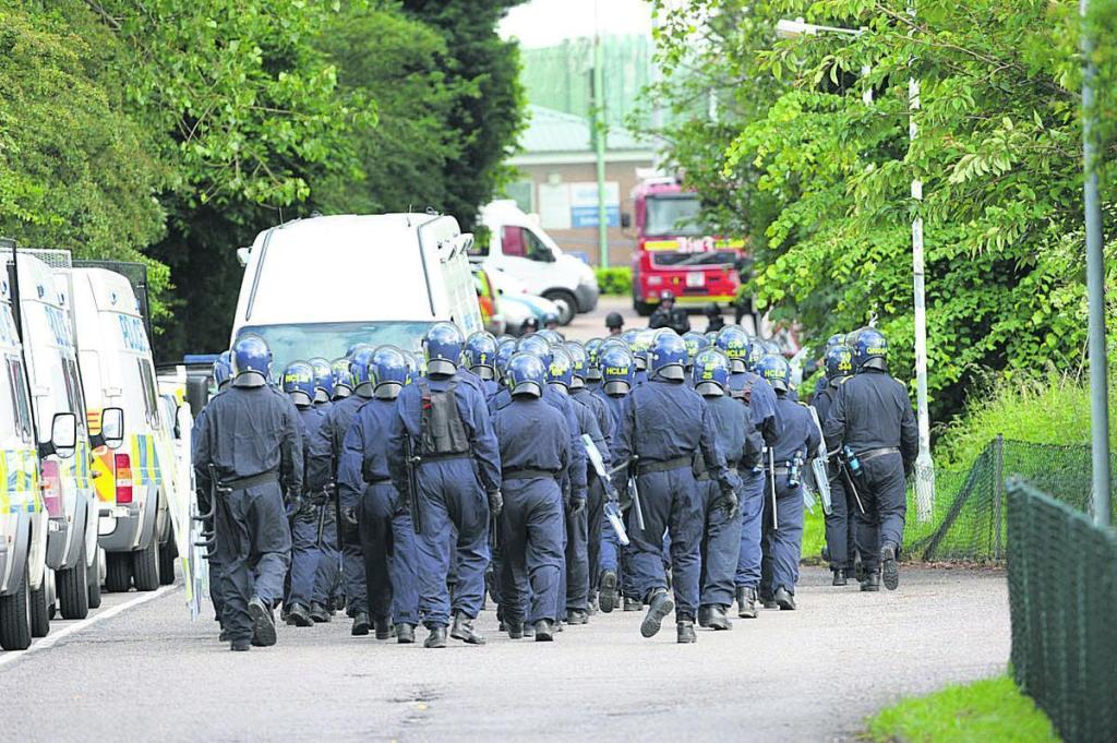 Phalanx of helmeted riot police approaching Campsfield House