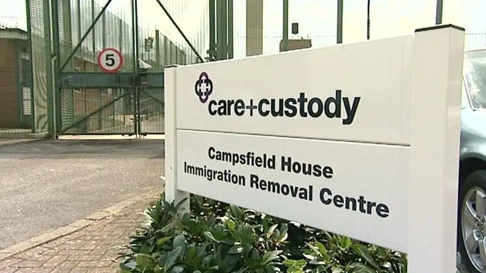 Board in front of Campsfield House with Mitie logo and ironic slogan "care+custody"