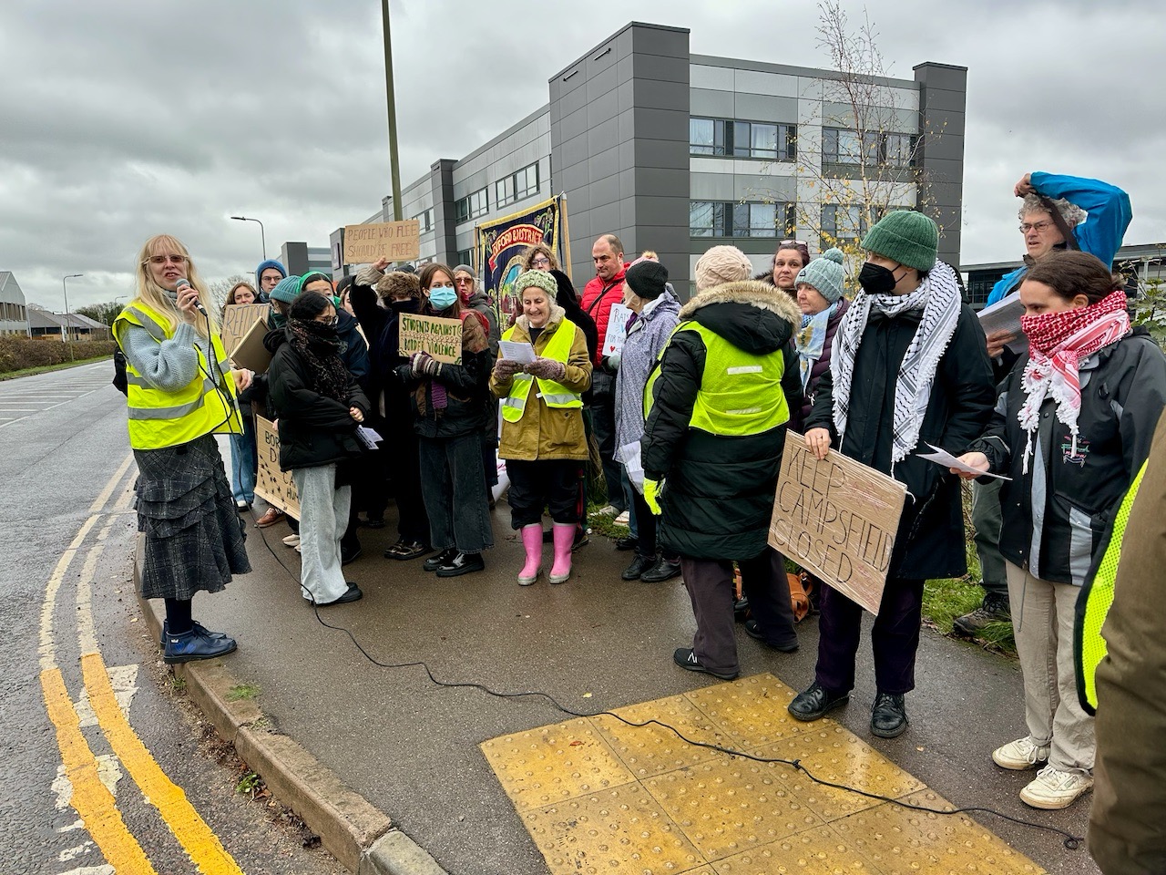 Emma Jones with microphone compéring the protest outside Campsfield House