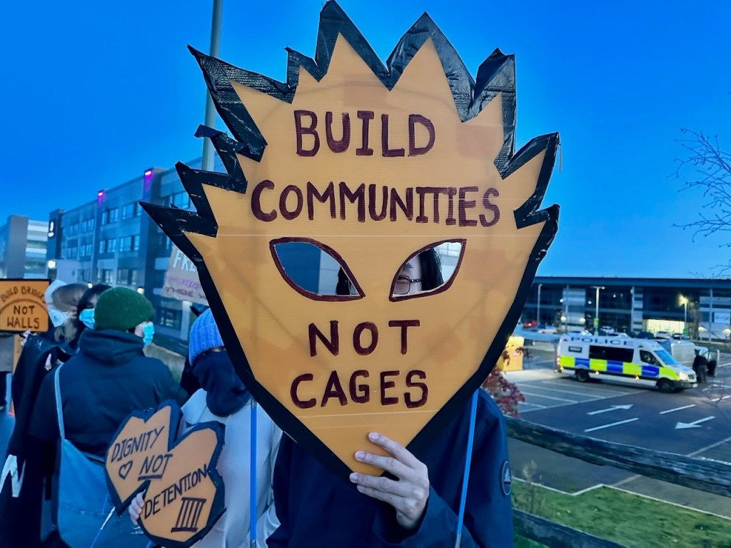 Placard reading "Build communities, not cages."