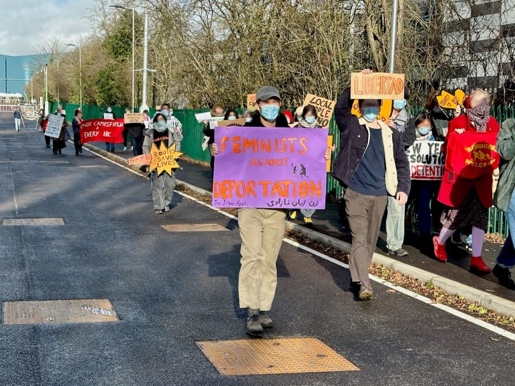 Protestors moving towards the detention centre, one with a sign reading "Feminists against deportation"