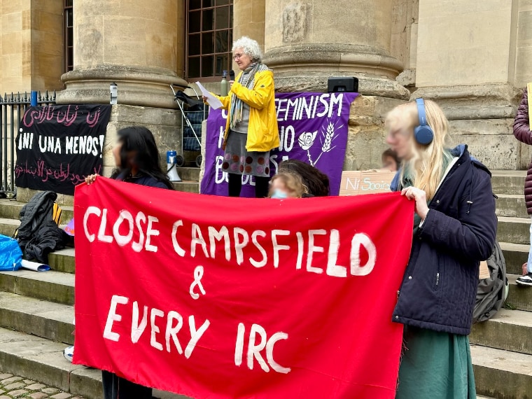 Liz Peretz of the Coalition to Close Campsfield addressing supporters at the Feminism Knows No Borders protest at the Clarendon Building, Broad Street, Oxford city centre on 8 March, International Women's Day 2026, behind a banner reading "Close Campsfield & Every IRC".