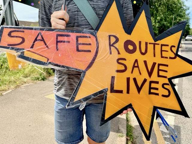 Placard reading "Safe routes save lives"